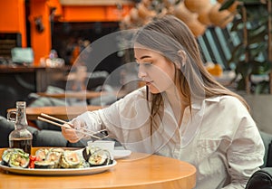 Young Woman eating and enjoying fresh sushi