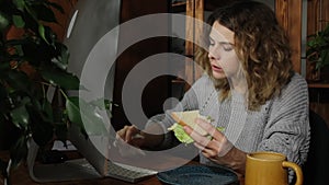 Young woman eating fast food while working at computer