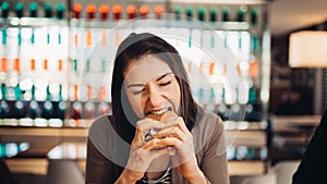 Young woman eating fatty hamburger.Craving fast food.Enjoying guilty pleasure,eating junk food.Satisfied expression.Breaking diet
