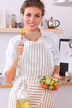 Young woman eating fresh salad in modern kitchen