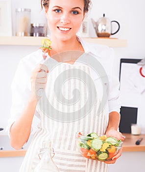 Young woman eating fresh salad in modern kitchen