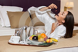 Young woman eating fruits on bed