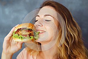 Young woman eating greedily delicious burger