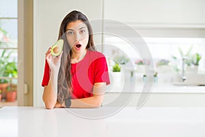 Young woman eating healthy avocado scared in shock with a surprise face, afraid and excited with fear expression