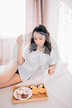 Young woman eating healthy breakfast in bed