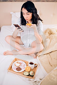Young woman eating healthy breakfast in bed