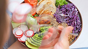 Young woman is eating a healthy salad bowl.