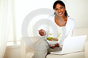 Young woman eating healthy salad looking at you