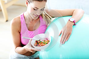 Young woman eating healthy salad after workout