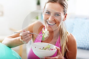 Young woman eating healthy salad after workout