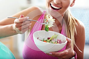 Young woman eating healthy salad after workout