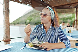 Young woman eating oyster in an outdoor restaurant