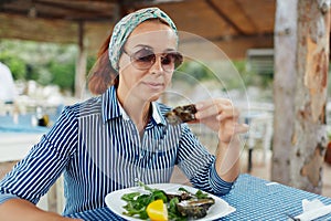Young woman eating oyster in an outdoor restaurant