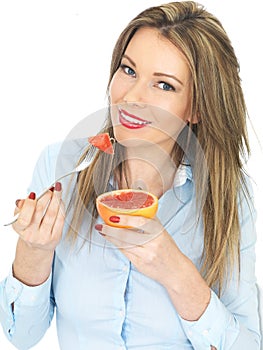 Young Woman Eating a Pink Grapefruit