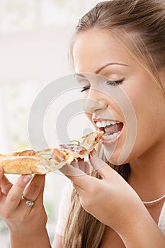 Young woman eating pizza slice