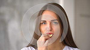 Young woman eating potato chips at gray background