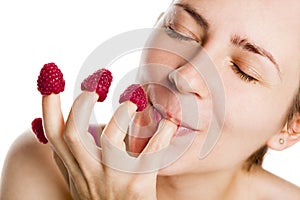 Young woman eating raspberries from fingers.