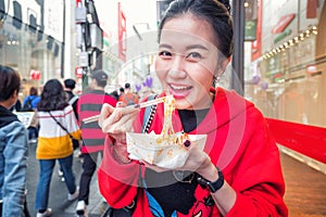 Young woman eating Roasted lobster with cheese at Myeong-dong street food in Seoul, South Korea photo