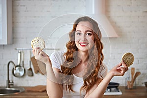 Young woman eating rye cracker crisp bread in the kitchen. Healthy Lifestyle. Health, Beauty, Diet Concept