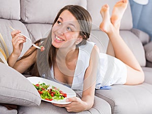 Young woman is eating salad because she being on vegetable diet