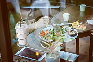 Young woman eating salad and beverage in cafe