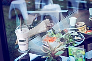 Young woman eating salad and beverage in cafe