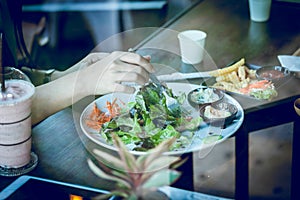 Young woman eating salad and beverage in cafe