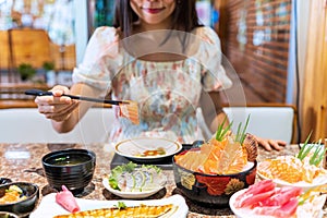 Young woman eating sashimi set in japanese restaurant