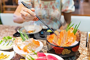 Young woman eating sashimi set in japanese restaurant