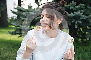 A young woman eating sushi in the park, picnic in nature.
