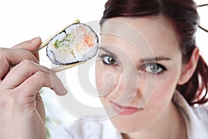 Young woman eating a sushi piece against a white