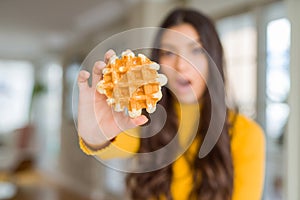 Young woman eating sweet waffle pastry scared in shock with a surprise face, afraid and excited with fear expression