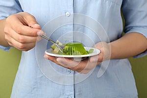 Young woman eating tasty kiwi jelly on background, closeup