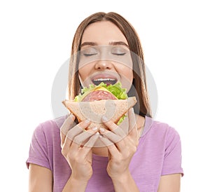 Young woman eating tasty sandwich on white