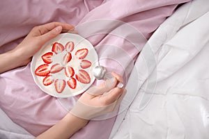 Young woman eating tasty yogurt with strawberries