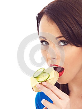 Young Woman Eating Toasted Crumpet with Cheese and Cucumber