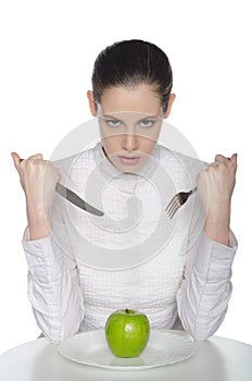 Young woman eats an apple with a knife and fork