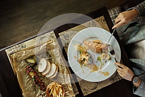 Young woman eats salmon fillet and fish tartare at an elegantly laid table in a restaurant. Health food. Top view