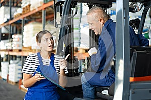 Young woman and elderly man working on loader check documents