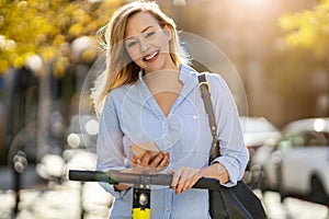 Young woman with electric scooter and smartphone in the city