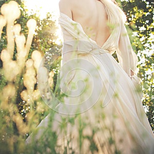 Young woman in elegant dress, bare back,  summer day in field