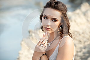 Young woman in elegant dress on the beach at sunset close up portrait
