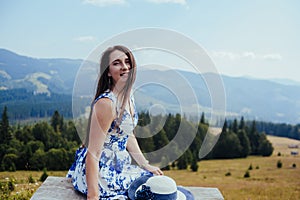 Young woman in elegant dress resting on the bench in the mountains