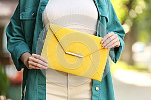 Young woman with elegant envelope bag on summer day, closeup