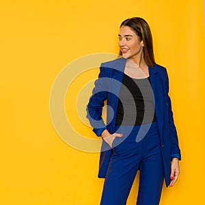 Young woman in elegant oversize navy blue jacket is posing with hand in pocket