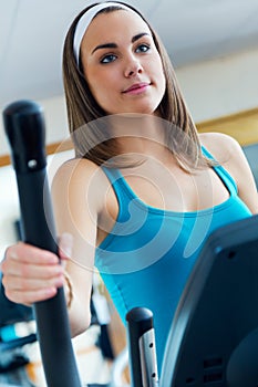 Young woman with elliptic machine in the gym.