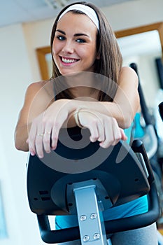 Young woman with elliptic machine in the gym.