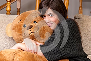 Young woman embrace teddy bear sitting sofa close