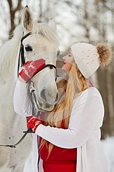 Young woman embraces and strokes horse muzzle in photo