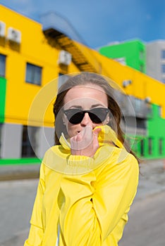 A young woman embracing the cold spring weather snuggling into her warm yellow jacket strolling along a street